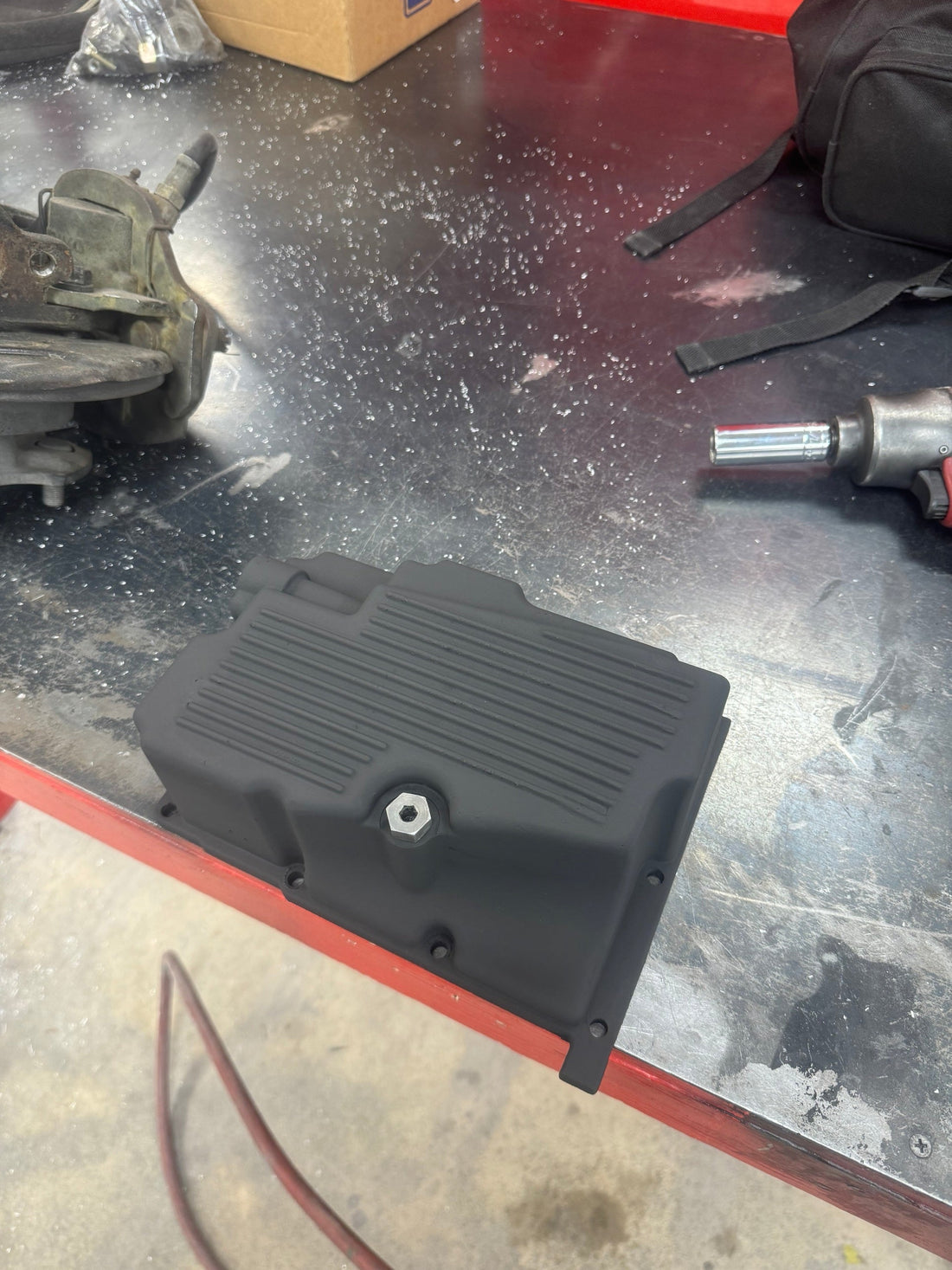 Finished matte black Harley Dyna oil pan after TIG weld repair and paint, with no visible repair