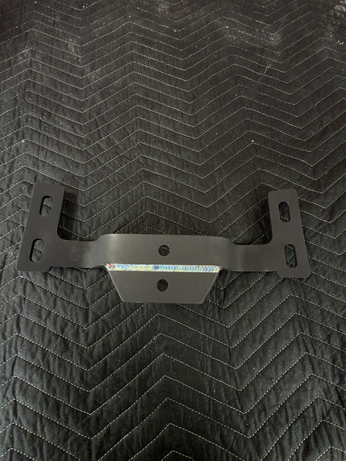 Black-coated custom steel bracket with a TIG weld along the center gusset