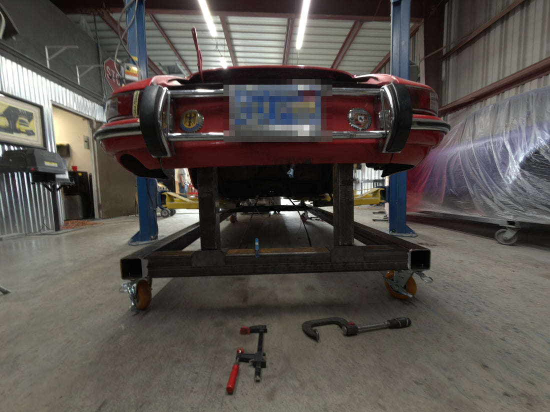 Classic Porsche 911 raised on a custom rolling steel chassis jig in the shop