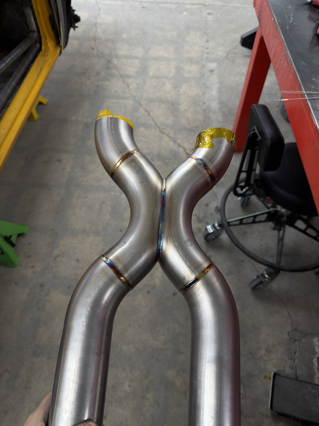 Custom stainless steel X-pipe with TIG welds showing heat-tint colors